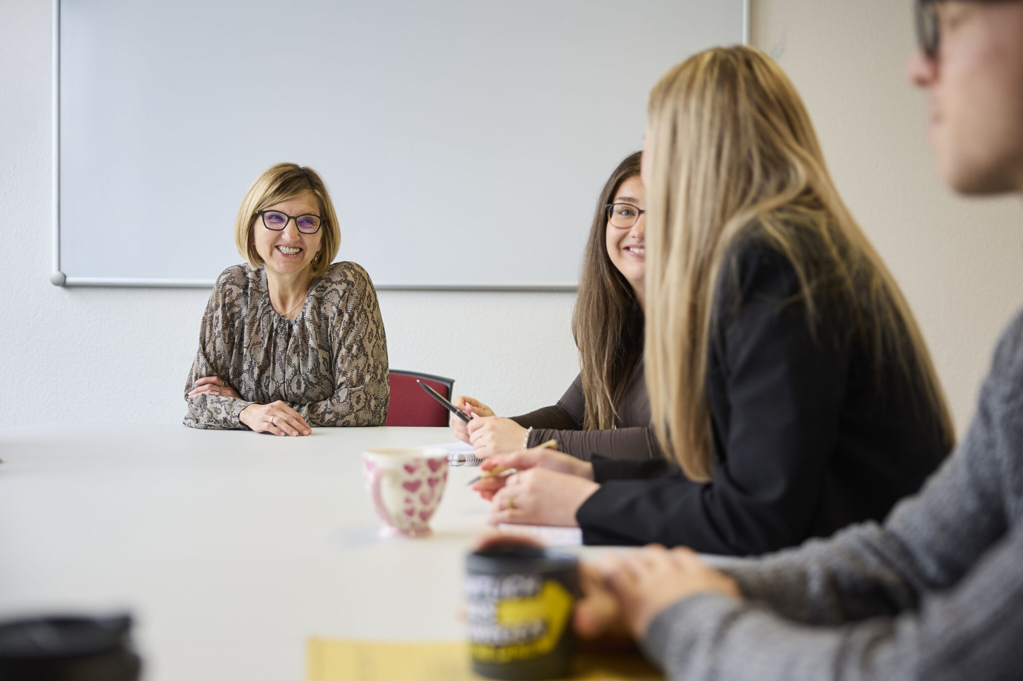 Mehrere Frauen sitzen gemeinsam an einem Tisch in einem Besprechungsraum und führen ein Gespräch.