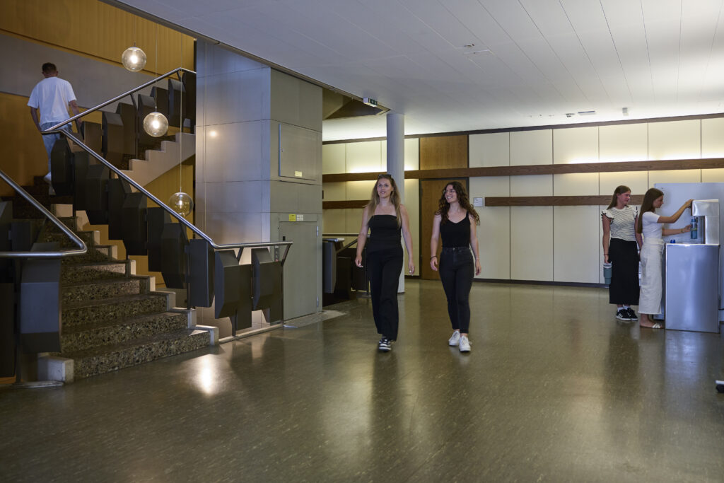 Studierende bewegen sich durch die Eingangshalle eines Hochschulgebäudes.